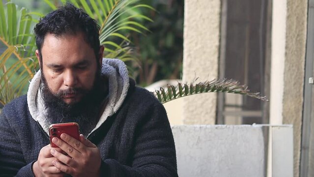 Sleepless disheveled man using his cellphone in the morning