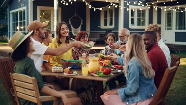 Big Family and Friends Celebrating Outside in a Backyard at Home. Diverse Group of Children, Adults and Old People Gathered at a Table, Having Fun, Eating Vegan Meals.