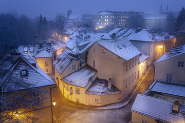 View of New World district with two streets and the house on the corner illuminated with lanterns in the winter snowy morning. Winter. Snow. Travel. Prague, Czech Republic.