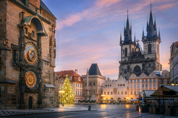 Old Town Square in de vroege ochtend met astronomische klok op de voorgrond en Tyn-tempel met kerstboom op de achtergrond in Praag tijdens de kerstperiode.