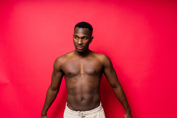 One young handsome african man topless portrait in studio on red background