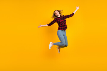 Fototapeta na wymiar Full length of cheerful wavy-haired girl jumping having fun rising hands isolated on bright vibrant color background