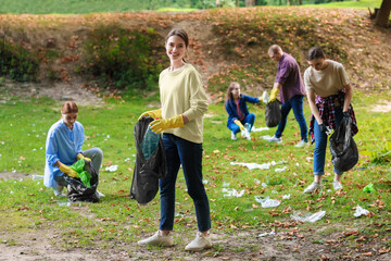 Group of people with plastic bags collecting garbage in park
