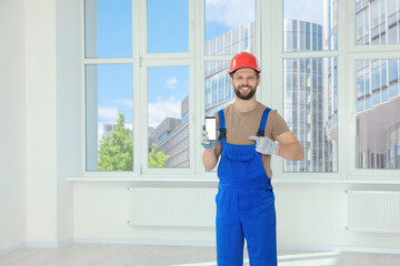 Professional repairman in uniform with phone indoors, space for text