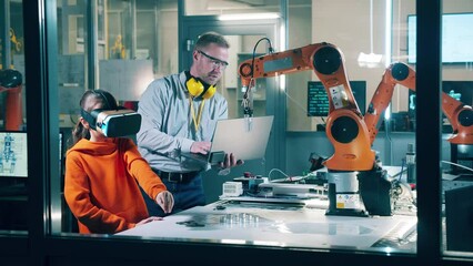 A girl in VR-glasses operating robotic arm. Technology, education concept.