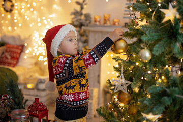 Cute child, boy, playing in decorated room for Christmas, decorating christmas tree