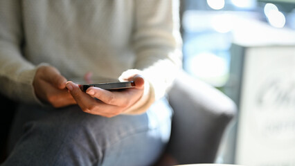 A female sitting in the coffee shop, using her smartphone to chat with her friends. cropped shot