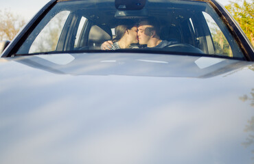 Smiling young couple inside a car. Kissing in the car