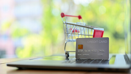 A credit card and shopping cart are on keyboard laptop. online shopping and credit card payment