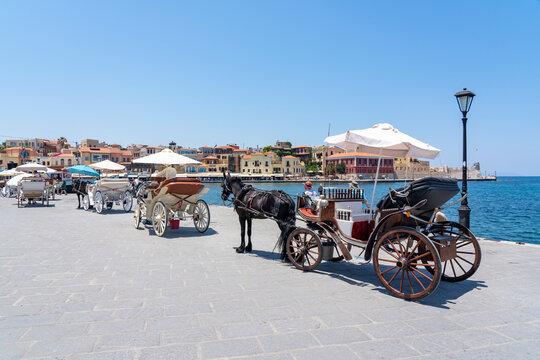 Many horse carriages are waiting in the harbor for new tourists to tour the old town of Chania, Crete, Greece
