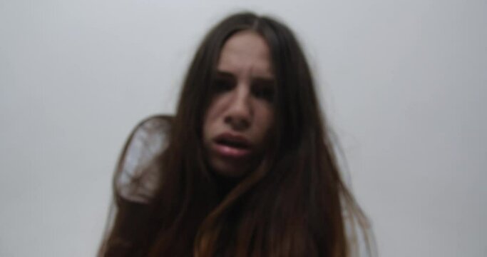 Extreme close up  of teenager girl with  long red hair, dressed in straitjacket, barefoot, tied with straps, sits in the corner of Ward in mental hospital.exacerbation of schizophrenia