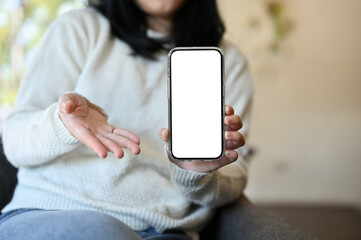 An Asian woman showing her smartphone white screen mockup to camera. cropped image
