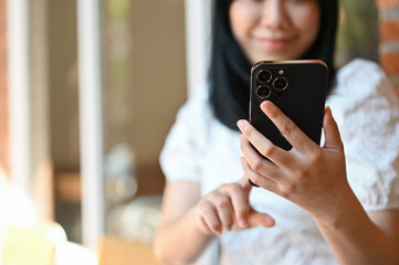 Asian woman touching on her phone screen, using her smartphone, scrolling on her social media