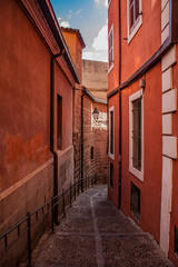 Exterior view of historical red buildings in the old town of Toledo, the former capital of Spain in Castile–La Mancha region, Europe. Typical Spanish narrow street with vibrant colorful houses.