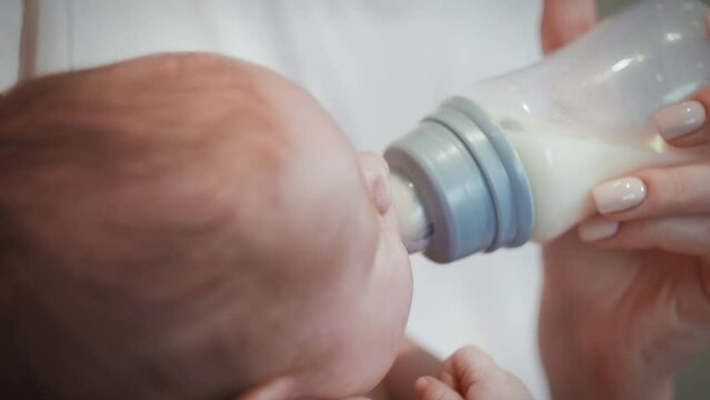 Mother feeds the baby from a bottle with a pacifier.