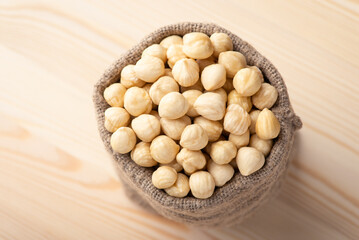 Peeled hazelnuts in linen bag. Tasty hazelnuts in small sack on wooden table