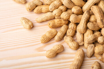 Unpeeled peanuts on wooden table. Tasty dried and fried peanuts on wooden background