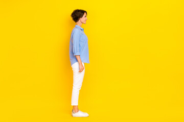 Fototapeta na wymiar Full length photo of cheerful good mood lady wear blue shirt looking empty space isolated yellow color background