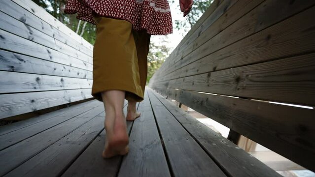 travel woman walks barefoot on a long sea bridge at a summer sunset