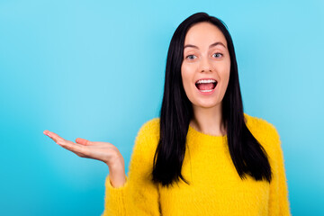 Portrait of attractive lovely cheerful brunette girl showing copy space isolated over bright blue color background.