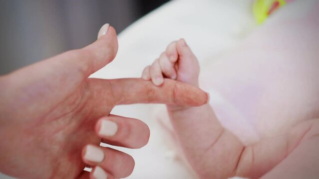 The hand of a small newborn baby touches the mother's hand.