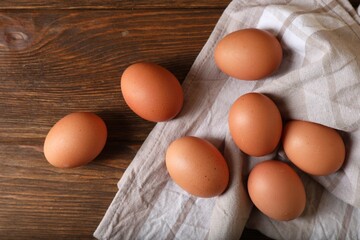 Raw brown chicken eggs on wooden table, flat lay