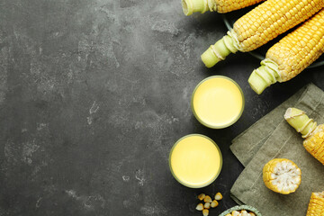 Flat lay composition with corn milk and cobs on grey table. Space for text