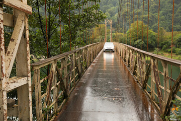 Beautiful view on rusty metal bridge over river and car in mountains