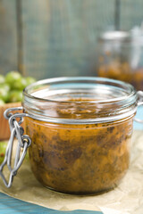 Jar of delicious gooseberry jam on blue wooden table, closeup