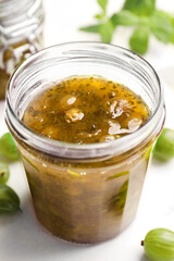 Jar of delicious gooseberry jam and fresh berries on white table, , closeup
