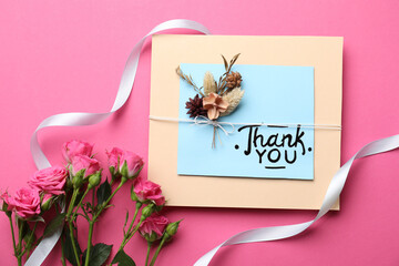 Card with phrase Thank You and beautiful flowers on pink background, flat lay