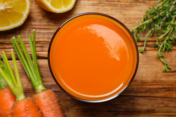 Glass of tasty carrot juice on wooden table, flat lay