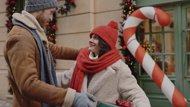 The man feeling happy is giving his girlfriend christmas gift and then hugging together. Surprised woman is happy because her husband gives her a big christmas gift