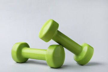 Two new green vinyl dumbbells on light background