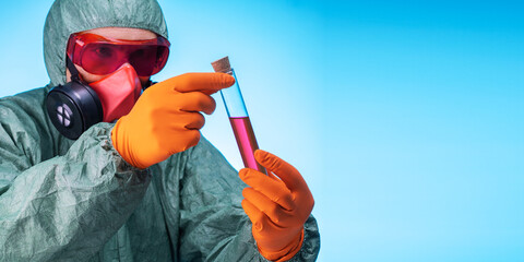 Man scientist in protective clothing and mask looks at test tubes in bio lab. banner with copy...