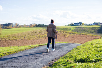 Lady walks on a countryside road nordic walking