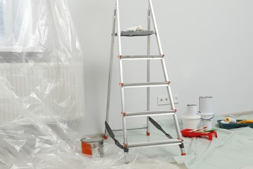 Metallic folding ladder and painting tools indoors