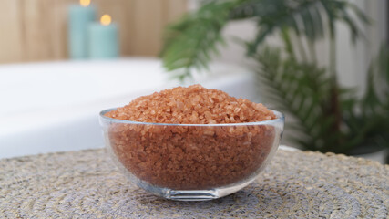 Glass bowl of bath salt on wicker mat in bathroom