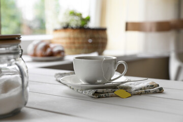 Tea bag in cup on white wooden table indoors