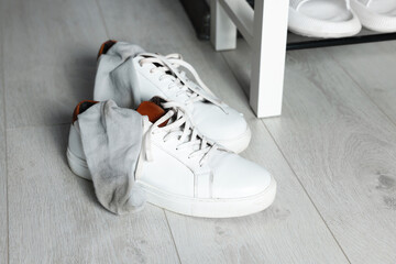 Sneakers with dirty socks on white wooden floor indoors - obrazy, fototapety, plakaty