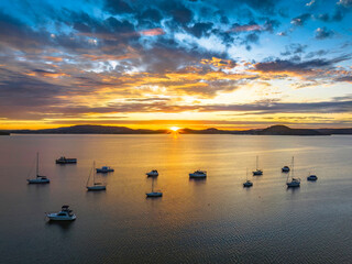 Aerial sunrise over the bay with boats, clouds and sunburst
