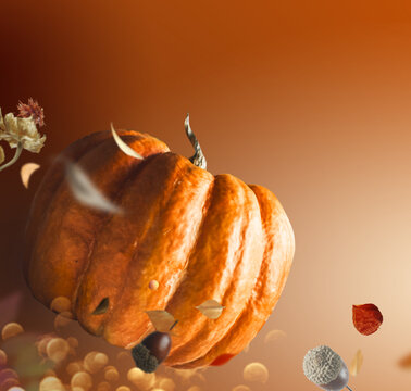 Flying pumpkin with falling leaves on brown background