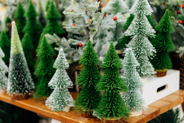 Various decorative artificial small Christmas trees in the store on the Christmas market. Preparing for winter holidays. Happy New year background. Selective focus.