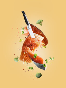 Flying salmon fish fillets with knife, herbs and spices. Creative seafood levitation