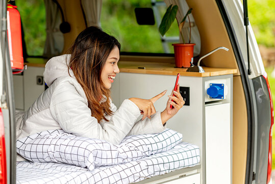 Asian woman using mobile phone inside the campervan