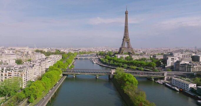 Aerial view of downtown Paris. A drone flies over the Seine River towards the Eiffel Tower. Green trees adorn the capital of France. Sunny day in Paris