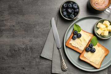 Delicious toasts served with butter, blueberries and coffee on grey wooden table, flat lay. Space for text