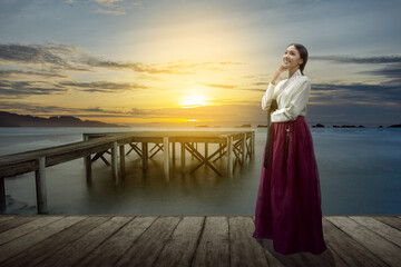 Asian woman wearing a traditional Korean national costume, Hanbok, standing on wooden pier