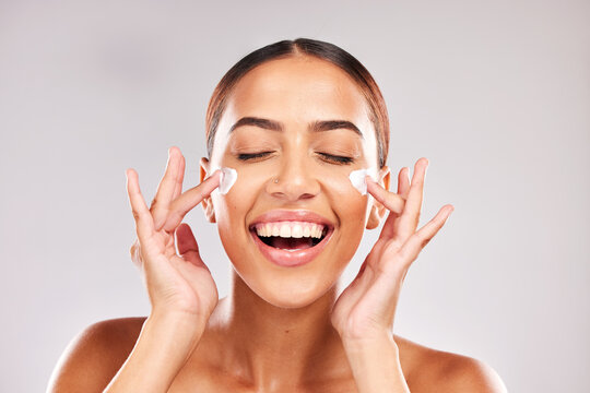 Skincare, beauty and woman with face cream in a studio doing a natural face and skin routine. Cosmetic, wellness and happy girl model with facial lotion, spf or sunscreen isolated by gray background.