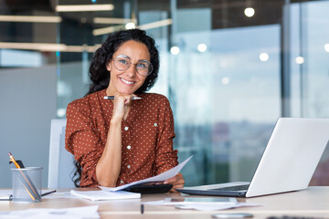 Portrait of happy and successful hispanic woman, businesswoman smiling and looking at camera...